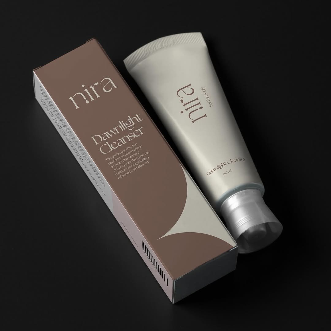 Nira Dawnlight Cleanser — mauve box and cream tube on dark backdrop